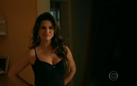 Laryssa Dias grava com cabelo solto, brinco de argola, regata preta e sorriso cínico como Viviane de Verdades Secretas