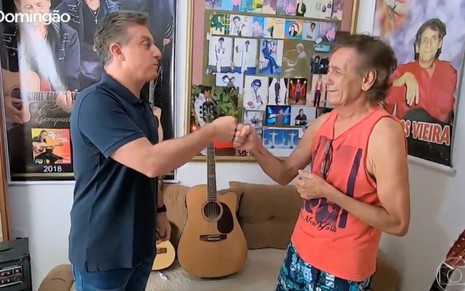 Luciano Huck cumprimenta o cantor brega Domingos Vieira em casa na Paraíba decorada com fotos na parede
