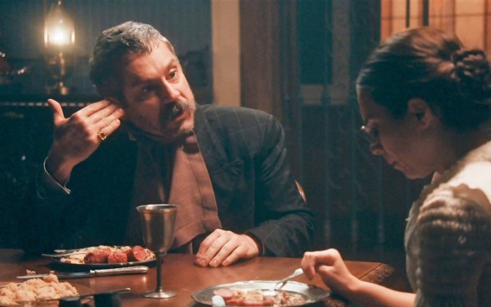 Tonico (Alexandre Nero) está sentado em mesa com  Dolores (Daphne Bozaski); ele a repreende na foto