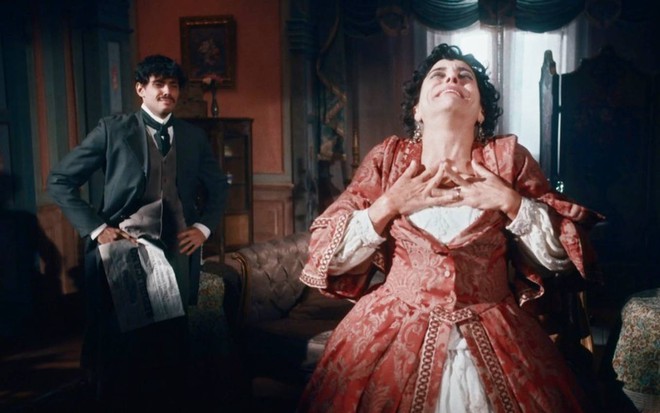 Atriz Paula Cohen coloca as mãos no peito e levanta a cabeça em cena de Nos Tempos do Imperador