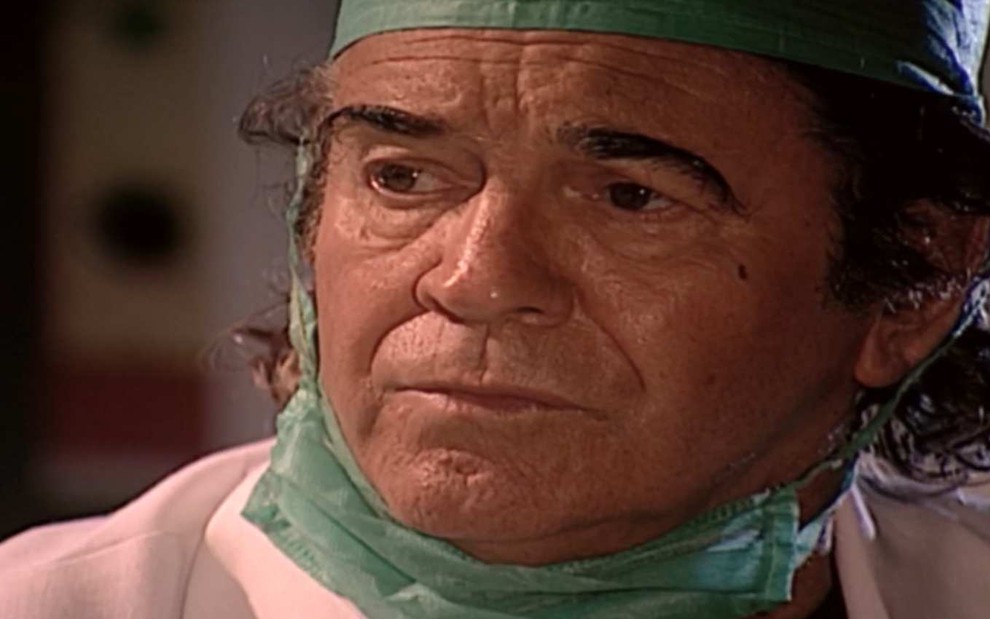 Ator Juca de Oliveira surge com máscara cirúrgica no queixo e olha para frente com cara de tenso em cena de O Clone