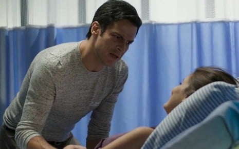 Ator Mateus Solano se debruça sobre cama de hospital e faz cara de espanto em cena da novela Pega Pega