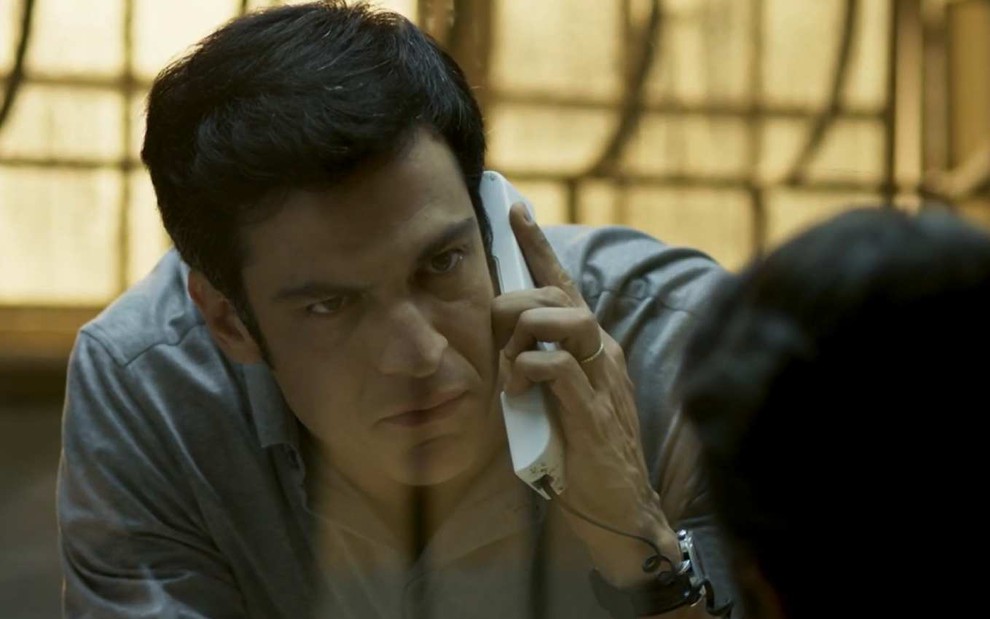 Ator Mateus Solano segura telefone e encara o ator Marcelo Serado em cena de Pega Pega