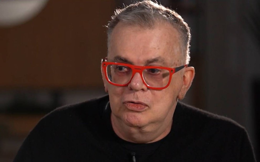 Autor Walcyr Carrasco usa óculos vermelho e olha para frente durante entrevista ao Fantástico