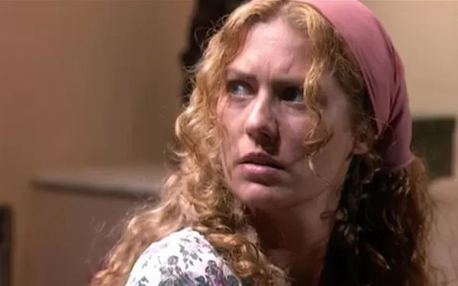 A atriz Patricia Pillar como Luana em O Rei do Gado; ela está usando um lenço e olhando para o lado, com cara de espantada
