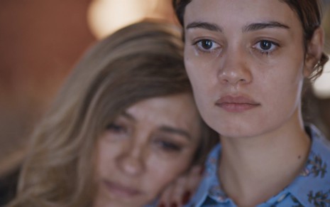 Regina Casé apoia o rosto no ombro de Sophie Charlote, que está chorando e em close, em cena da novela das Todas as Flores