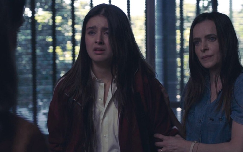 Lara (Júlia Byrro) está acompanhada de Araídes (Maria Luisa Mendonça) em escola; ela chora em cena de Verdades Secretas 2