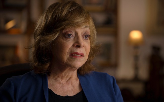 A autora Gloria Perez com expressão séria, durante fala à série documental Pacto Brutal