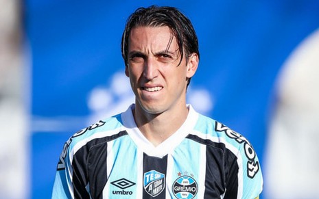 Geromel, do Grêmio, veste uniforme listrado em branco, azul e preto durante partida do time gaúcho