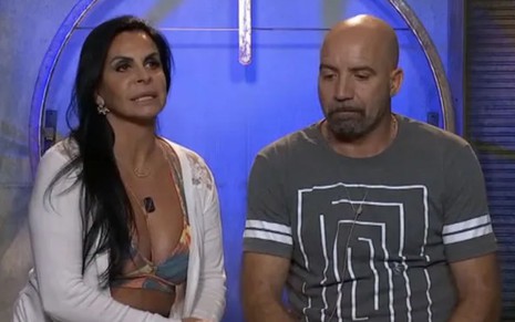 Gretchen e Carlos Marques sentados lado a lado no cenário do Power Couple Brasil