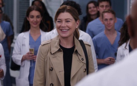 Ellen Pompeo sorri rodeada de pessoas em cena da 19ª temporada de Grey's Anatomy