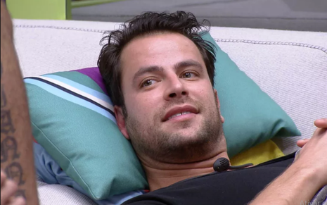 Gustavo Marsengo usa camiseta preta e está deitado no sofá da sala do Big Brother Brasil 22