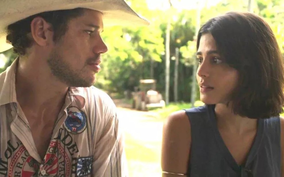 Os atores José Loreto e Julia Dalavia lado a lado, olhando um para o outro, em cena de Pantanal