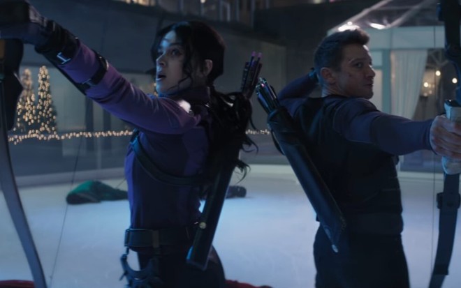 Hailee Steinfeld ao lado de Jeremy Renner segurando arco e flecha em cena de Gavião Arqueiro