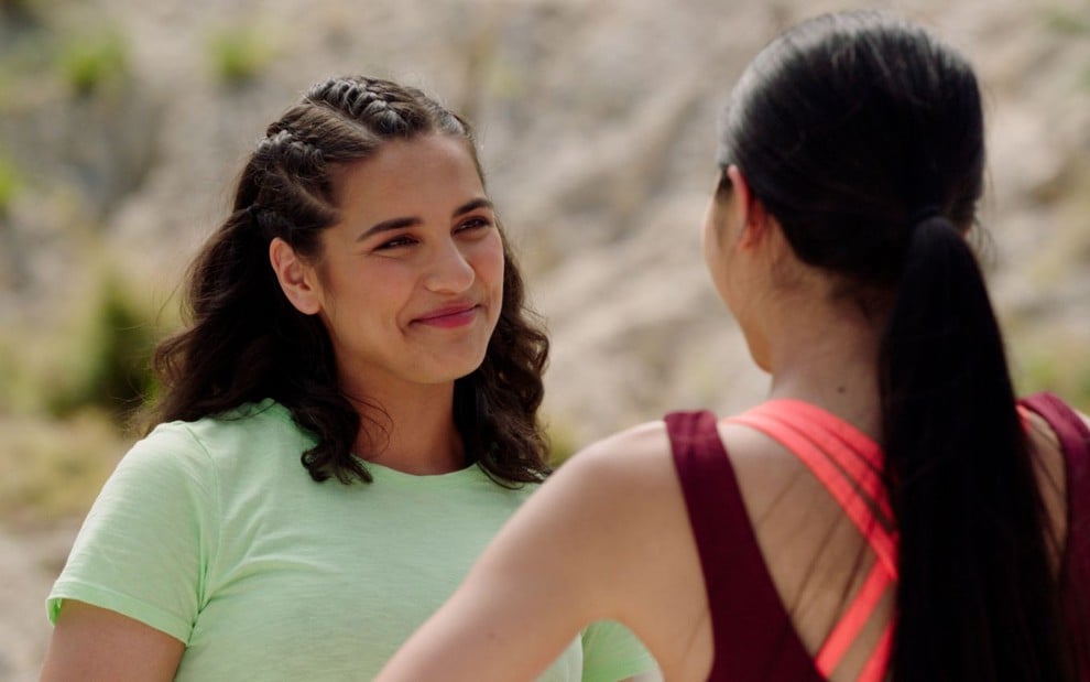 Tessa Rao sorri para Jacqueline Joe, que está de costas para a câmera; as duas vestem roupas de corrida em cena de Power Rangers Dino Fury