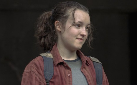 Ellie (Bella Ramsey) veste camisa vinho, camiseta cinza e mochila azul em The Last of Us