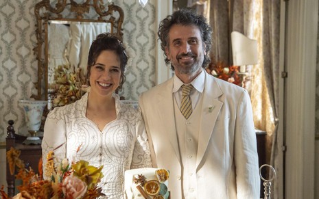 Os atores Paloma Duarte e Eriberto Leão como Heloísa e Leônidas em Além da Ilusão; eles estão vestidos de noivos e sorrindo para a foto