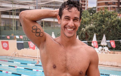 Sem camisa, Henrique Martins exibe tatuagem com os anéis olímpicos em seu braço