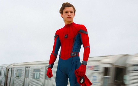 Vestido como Homem-Aranha, mas sem a máscara, Tom Holland olha para o horizonte com pose heroica