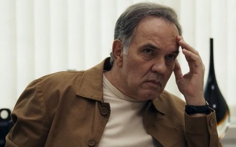 Humberto Martins com mão na testa e expressão séria em cena como Guerra na novela Travessia