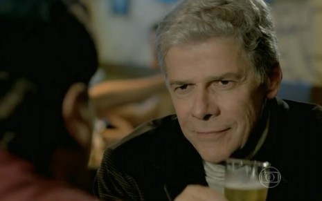 Cláudio (José Mayer) segura copo de cerveja em bar em cena de Império