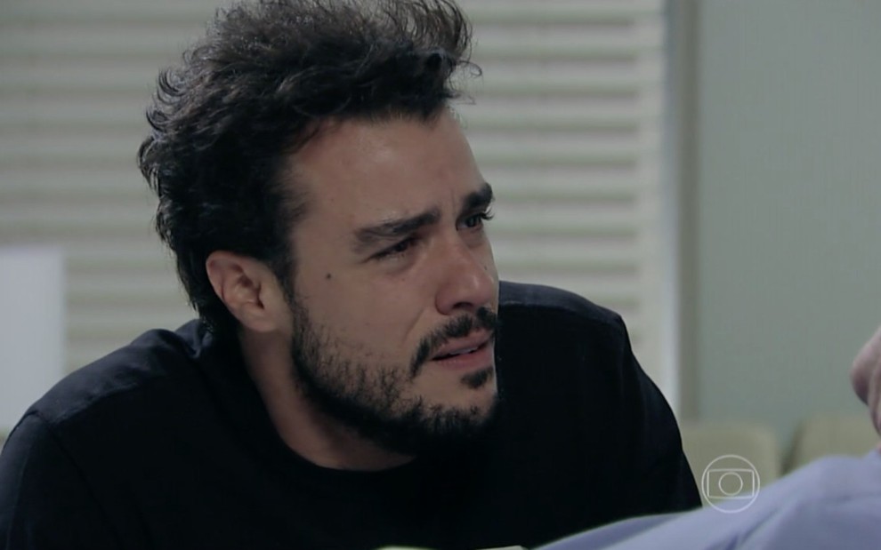 O ator Joaquim Lopes chorando ajoelhado a cama de hospital em cena de Império