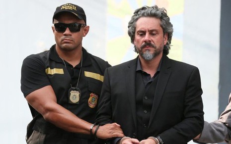 O ator Alexandre Nero sendo conduzido por figurante caracterizado como policial em cena da novela Império