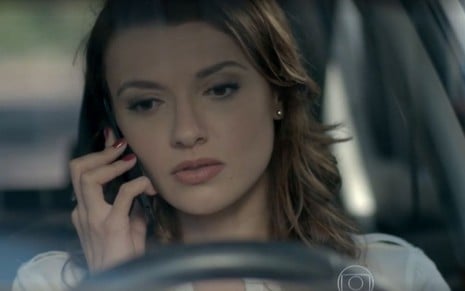 Helena (Júlia Fajardo) está dentro de carro falando ao celular em cena de Império