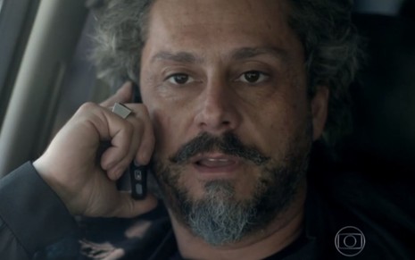 Alexandre Nero em cena de Império: personagem está caracterizado como José Alfredo, com telefone na orelha e olhar de atenção
