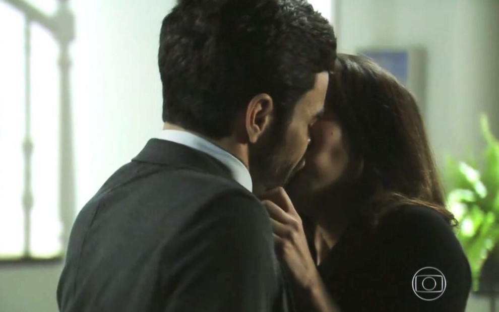 José Pedro (Caio Blat) beija Cora (Marjorie Estiano) na sala da casa da vilã em cena de Império