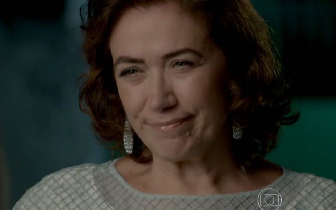 lilia Cabral olha para frente e faz sorriso irônico em cena de Império