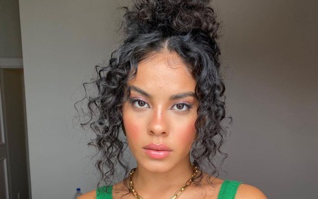 Bella Campos em foto publicada no Instagram: atriz está com penteado preso, cabelos cacheados, com maquiagem e regata verde