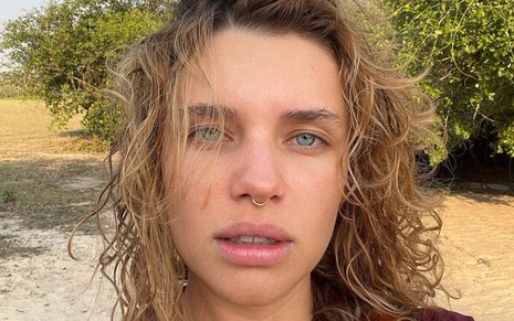 Bruna Linzmeyer durante gravações de Pantanal: atriz está com cabelo molhado, ao vento, e olha para frente