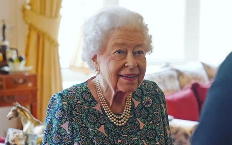 Rainha Elizabeth 2ª sorri em foto de divulgação, na qual usa vestido estampado e colar de pérolas