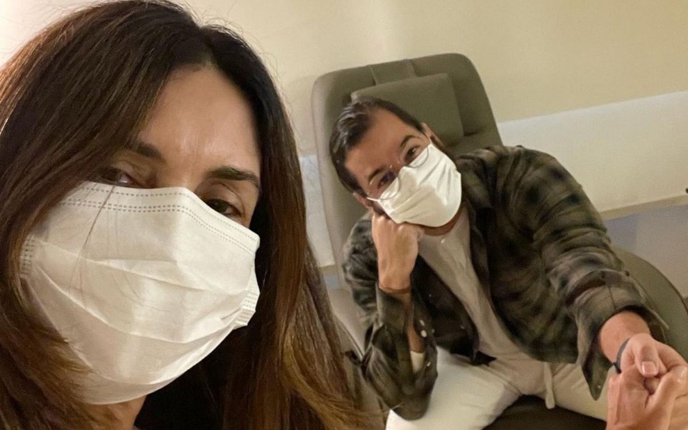 Fátima Bernardes e Túlio Gadêlha estão de mãos dadas em hospital; os dois usam máscaras de proteção