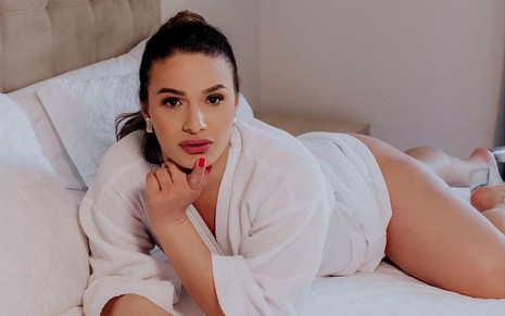 Glamour Garcia em foto publicada no Instagram: atriz está deitada em cama com roupão branco, ela coloca um dedo indicador no queixo