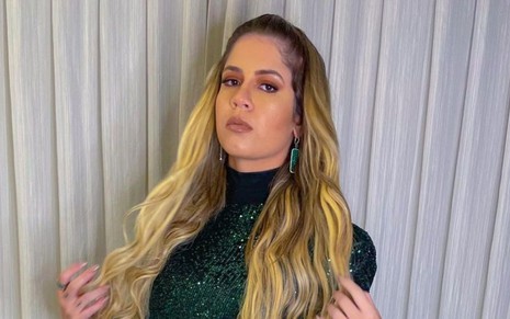 Marilia Mendonça em foto publicada no Instagram: cantora está com cabelos soltos, vestido verde de mangas e bota preta