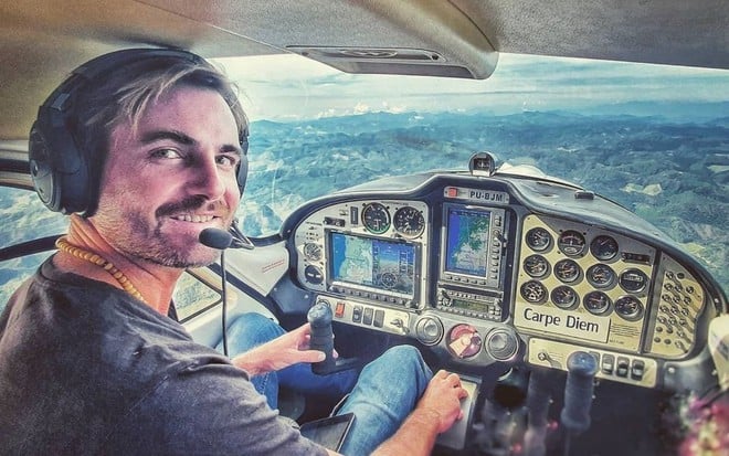 Max Fercondini em foto publicada no Instagram: ator está dentro de cabide de avião, usa fone e microfone acoplado, camisa preta e olha para câmera