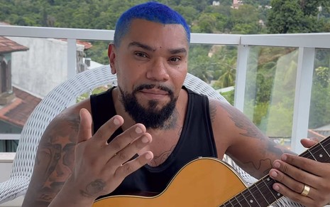 Naldo Benny com cabelo azul e violão no colo  em vídeo postado no Instagram