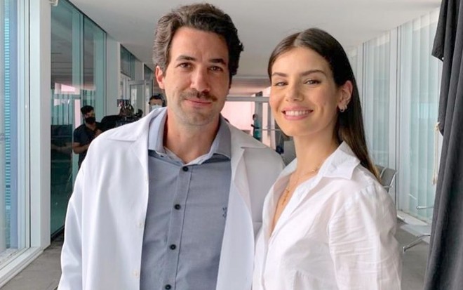 Rafael Queiroz veste jaleco e posa ao lado de Camila Queiroz nos bastidores de Verdades Secretas 2