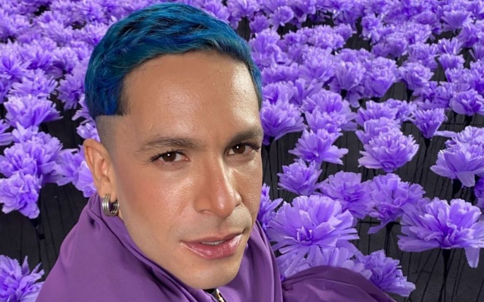 Rainer Cadete em foto publicada no Instagram: em close, ator para a câmera e está com o cabelo pintado de azul; cenário é todo roxo