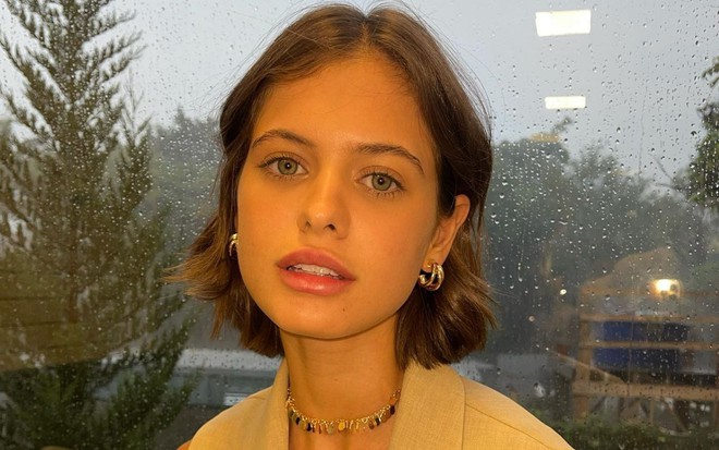 Sara Vidal usa cabelo curto na altura do queixo, olha para frente e está em meio ao verde