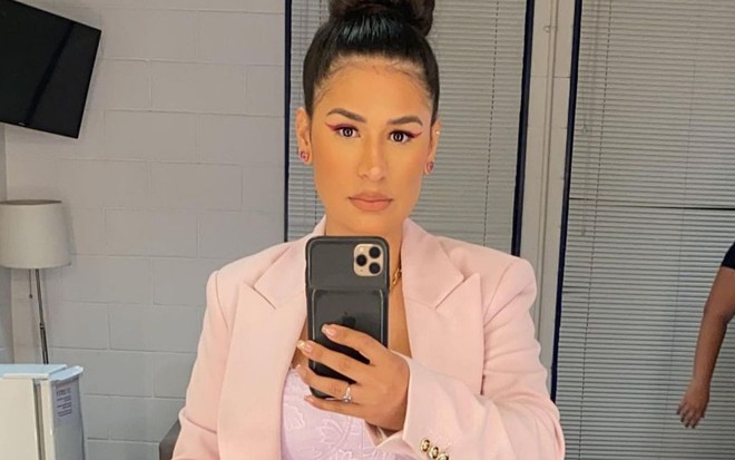 Simone Mendes posa em frente ao espelho; ela usa terno rosa e calça jeans