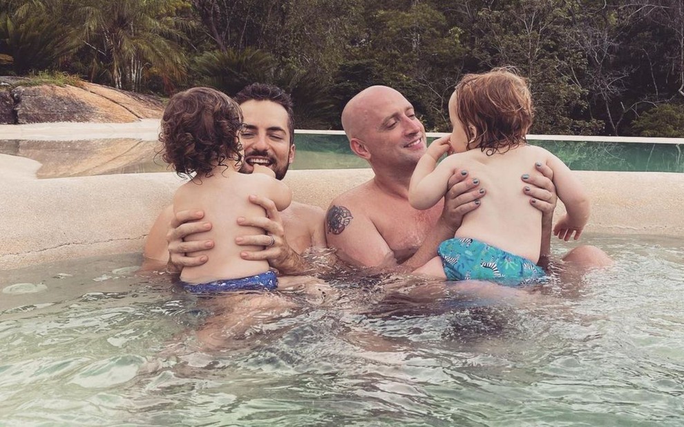 Foto do casal Thales Bretas e Paulo Gustavo com os filhos, Gael e Romeu, em uma piscina