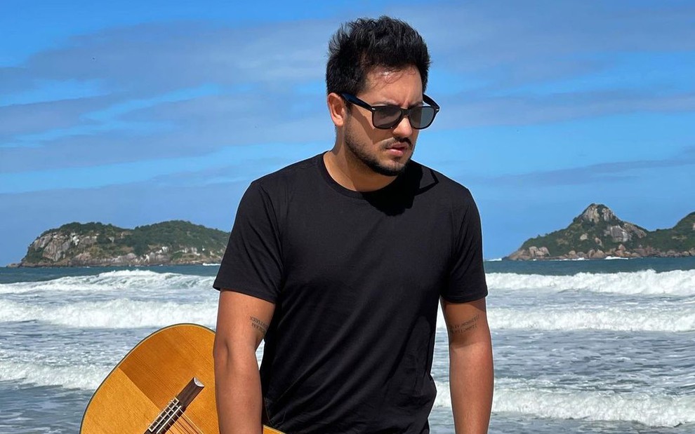 Thiago Bertoldo segura violão na praia em foto compartilhada no Instagram