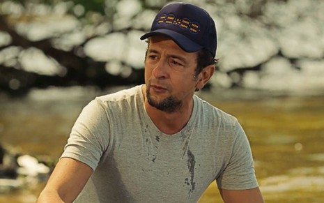 José Lucas (Irandhir Santos) está à beira de um rio em cena da novela Pantanal