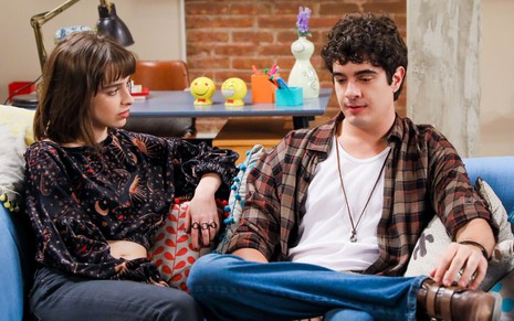 Raquel (Isabella Moreira) e André (Thiago Franzé) estão sentados em sofá