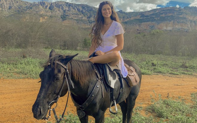 Isadora Cruz está em cima de um cavalo nos bastidores de gravação de Mar do Sertão