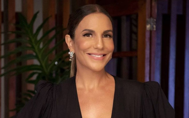 Ivete olha para a câmera, sorri e usa vestido preto