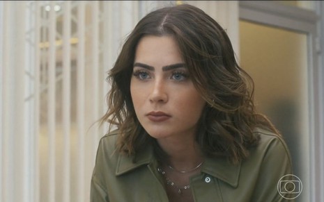 Em cena de Travessia, Jade Picon está com expressão de desprezo: ela usa blusa verde militar e olha para alguém